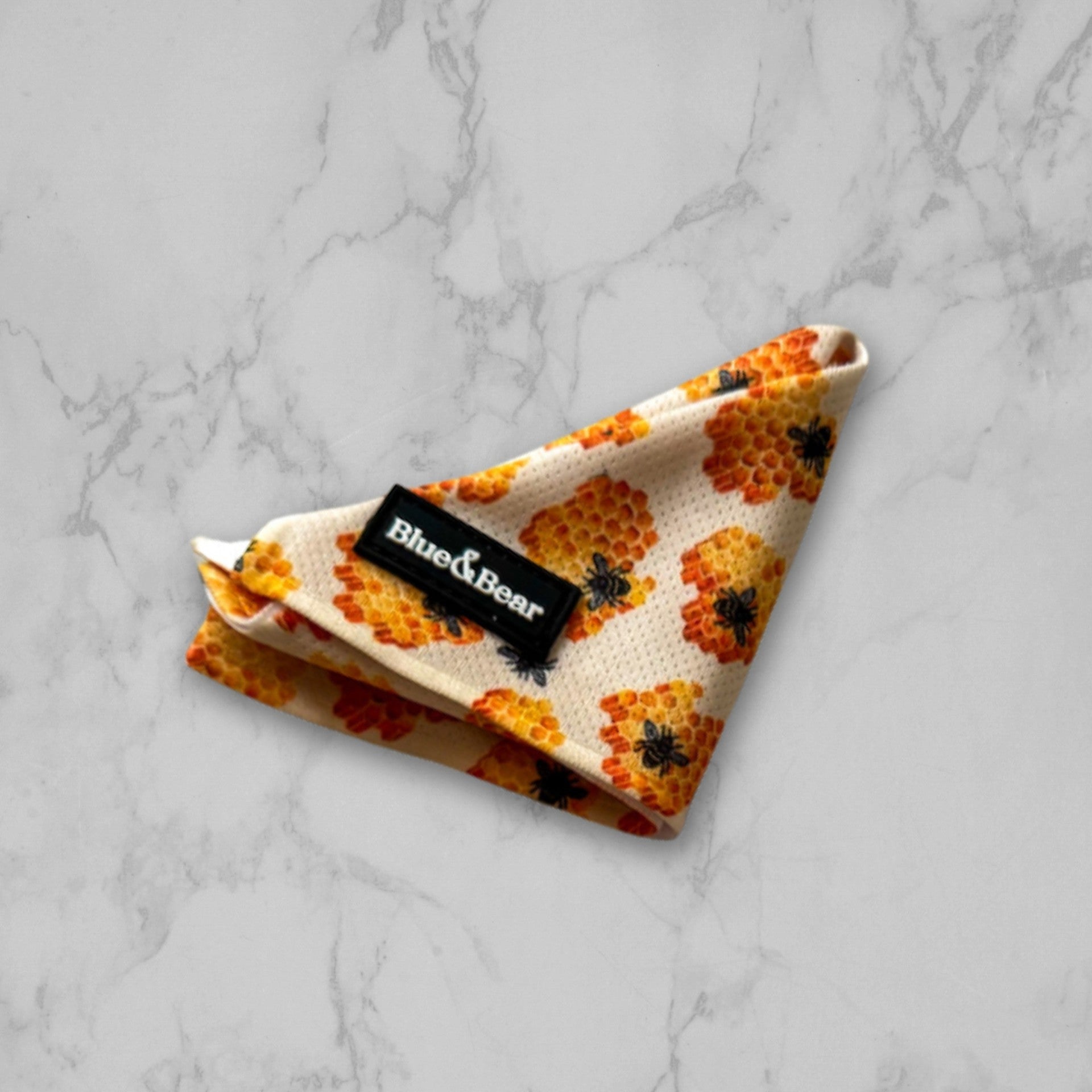 Yellow dog bandana with honey bee pattern on marble tile