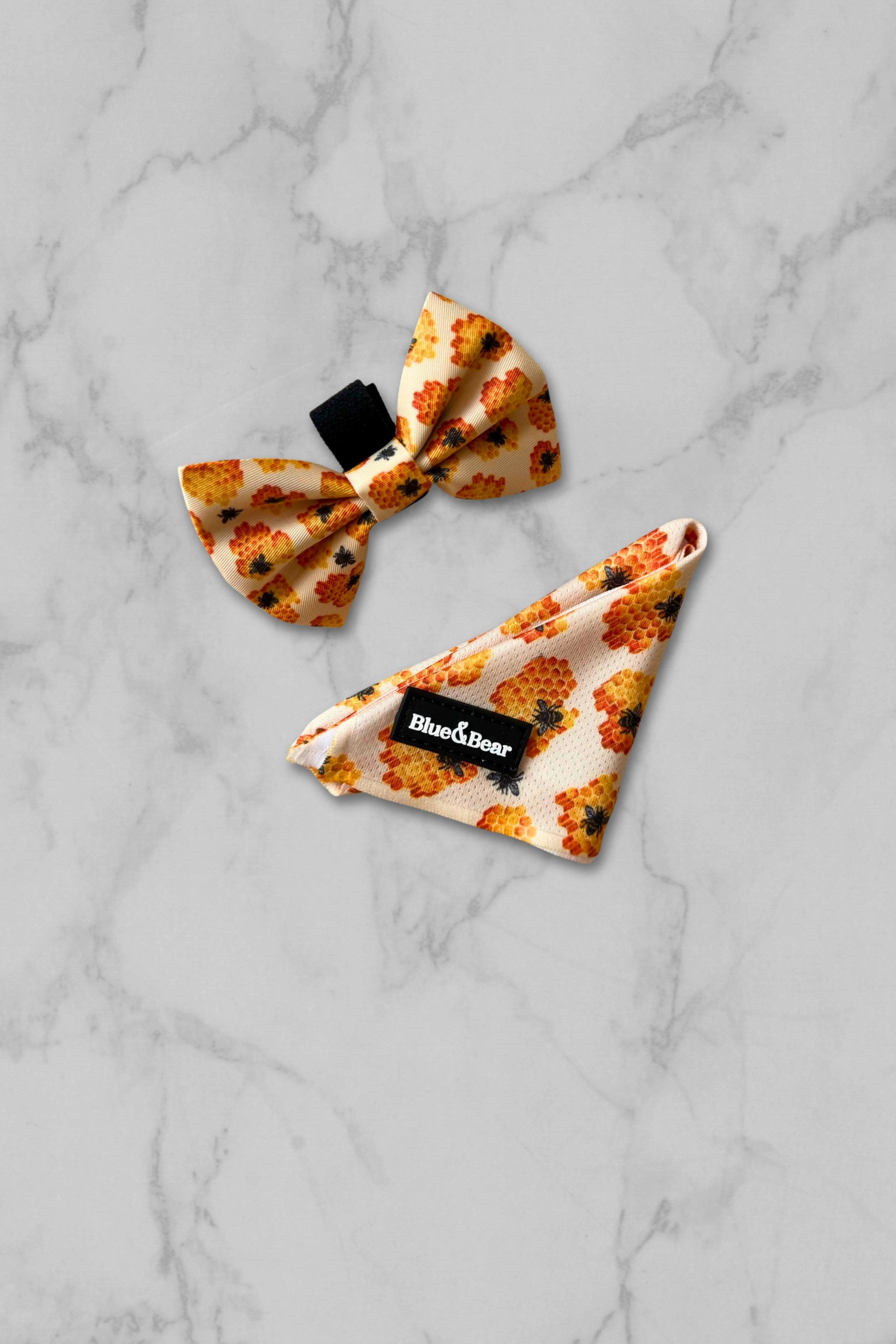 Yellow dog bandana with honey bee pattern and matching bow tie on marble tile