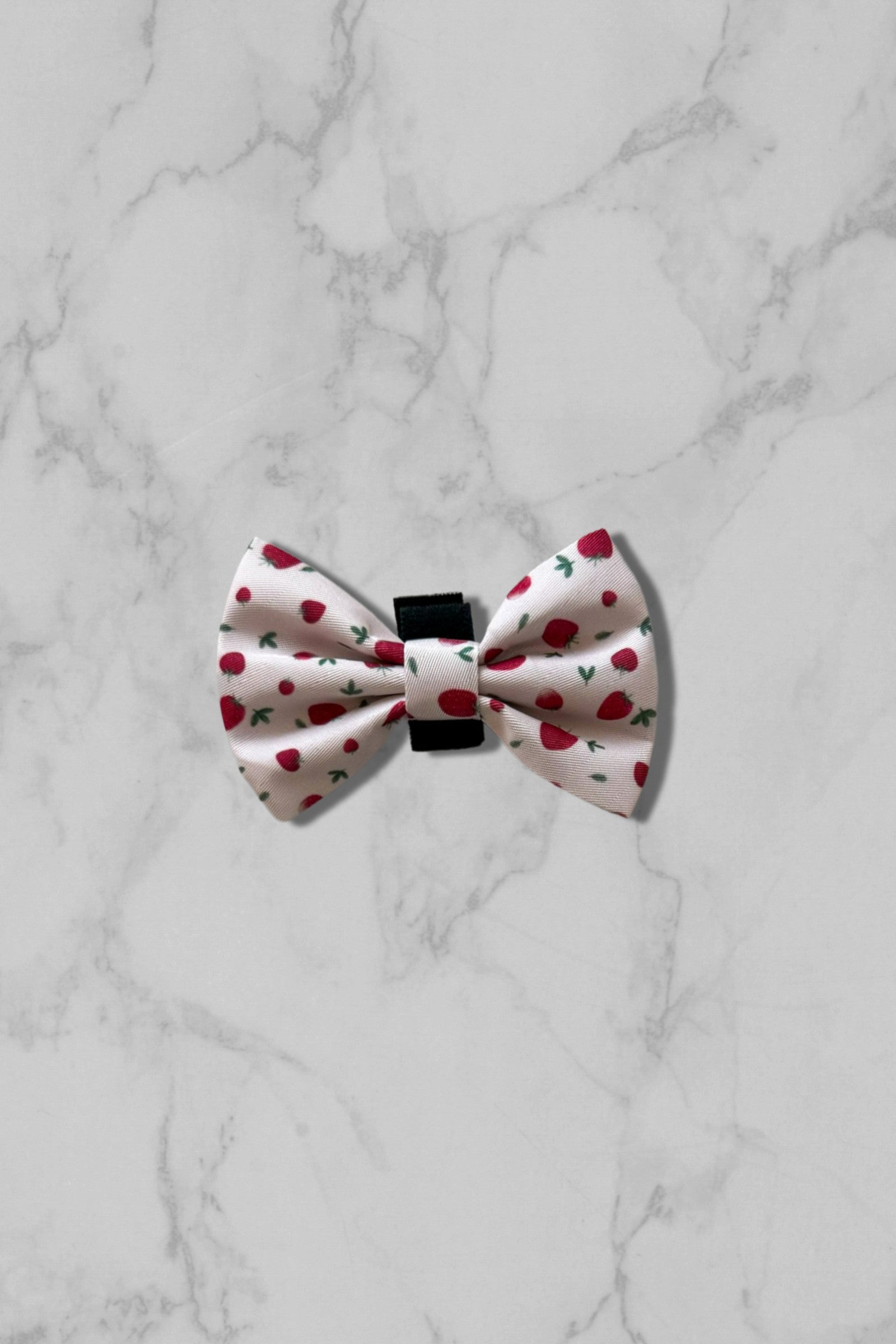 Pink bow tie with strawberry pattern on marble tile