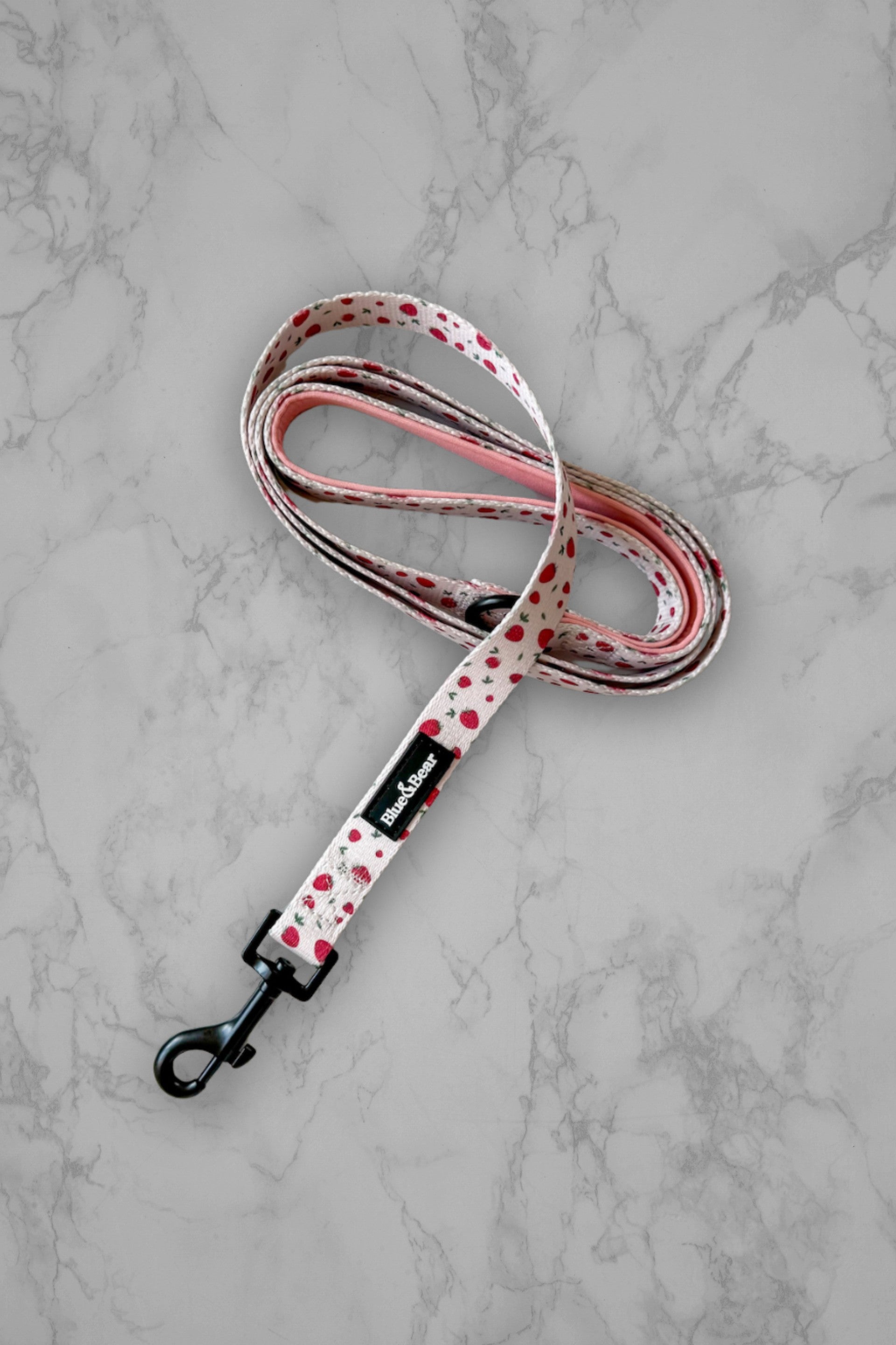 Pink dog lead with strawberry pattern on marble tile