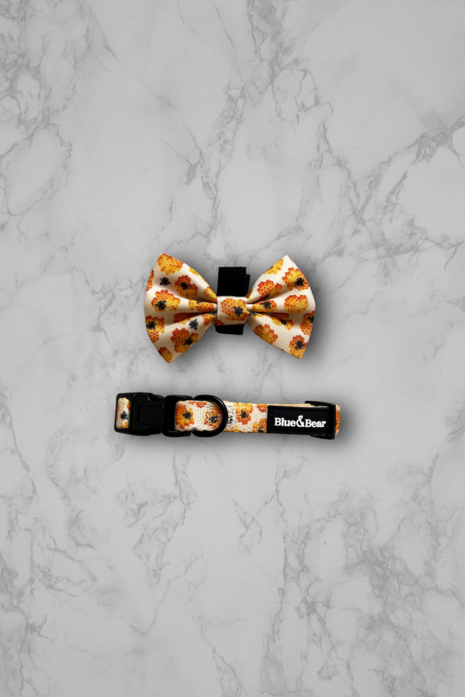 Yellow honey bee dog collar and bow tie on a marble tile