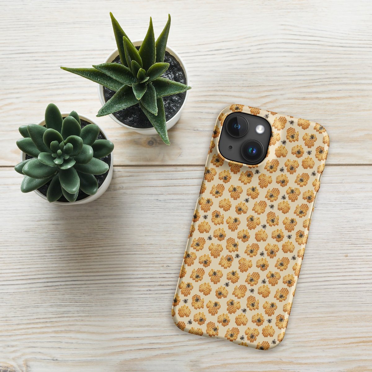 Yellow phone case with honeybee pattern on wooden table with plants